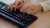 Hand tippt auf Computer-Tastatur