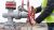 A man wearing a bright yellow vests turns a red wheel valve on a pipe