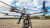 A bp team member wearing a white helmet stands directly behind a drone that is calibrating on the ground.