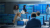 A team of six people work in a room filled with computer monitors